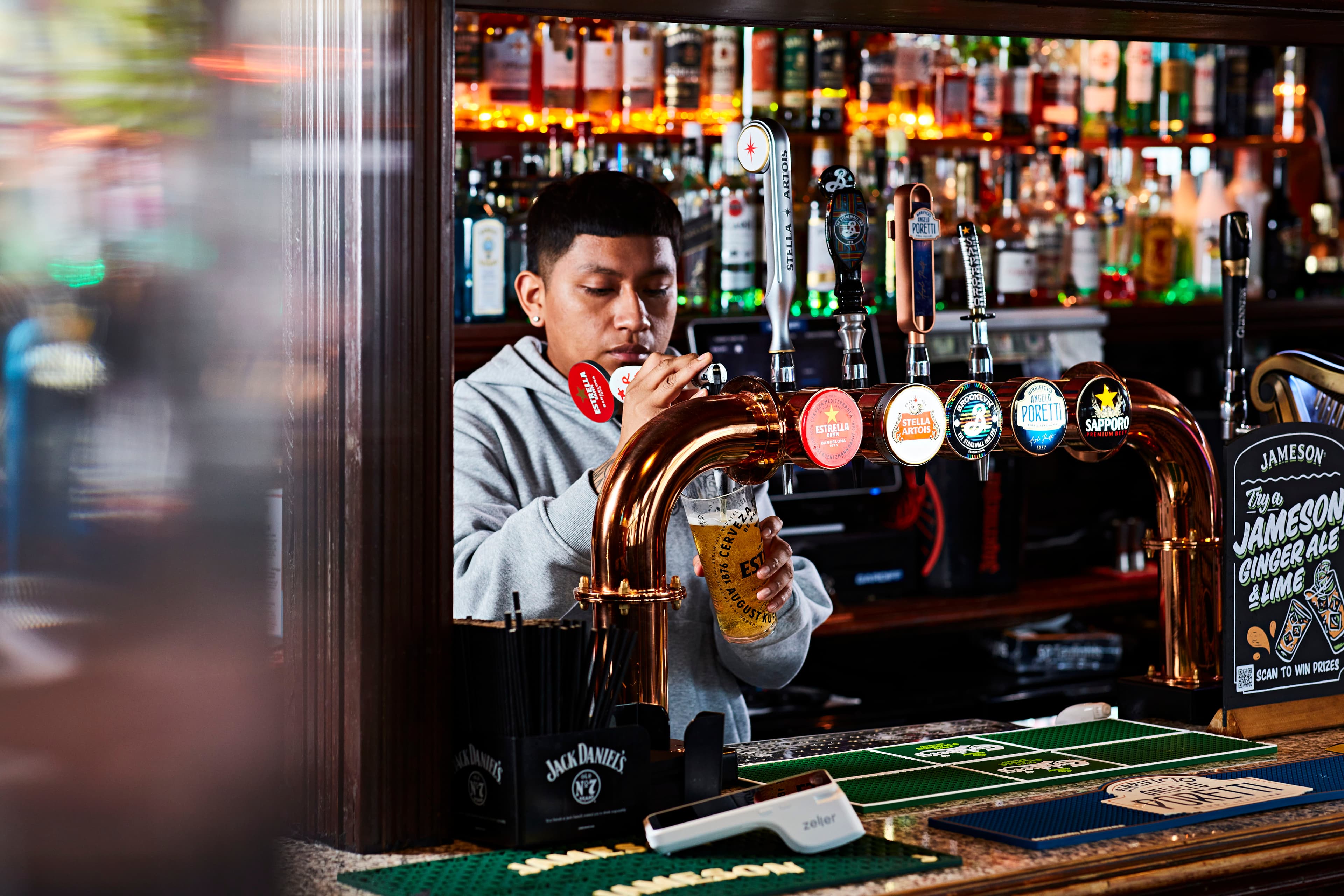 Bartender at a pub pouring a draft beer into a glass