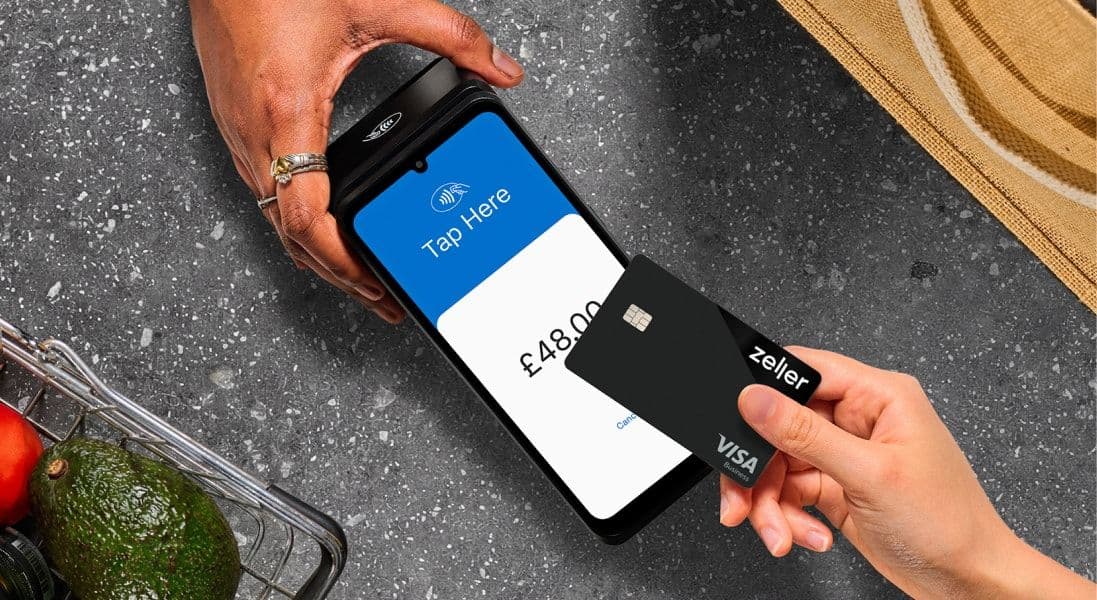 A person taps a black Zeller Visa card on a payment terminal showing "£48.00" beside groceries on a gray countertop.